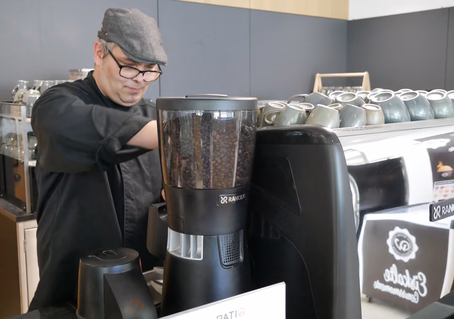 Mitarbeiter im Patio bereitet Kaffee fü+r einen Gast