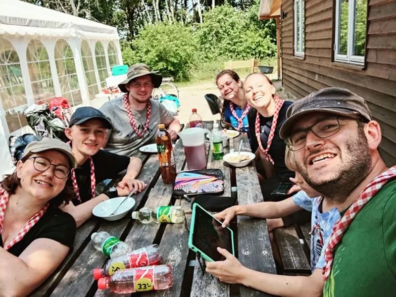 A group of scout leaders sitting around a picknick table having fun