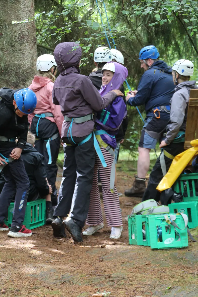 A group of kids preparing to climb a tree in safety gear