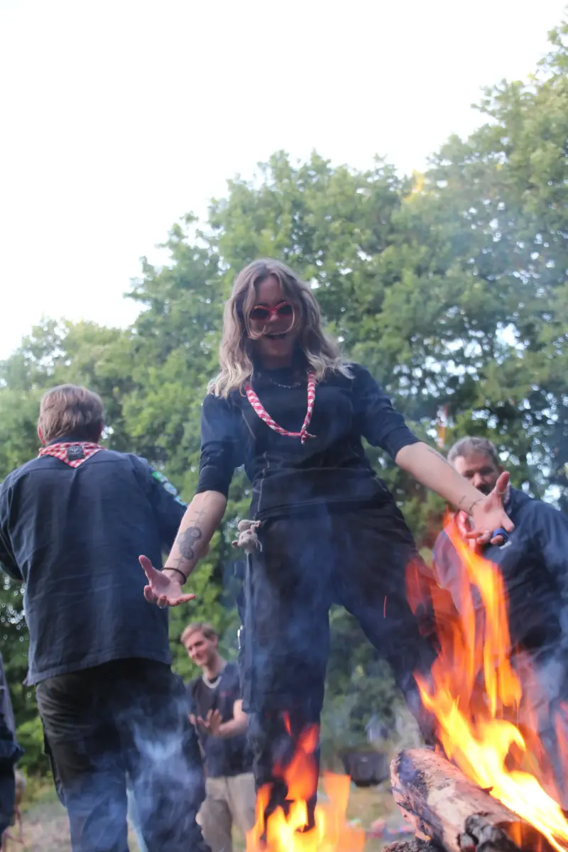 A young girl doing a silly pose in front of a bonfire