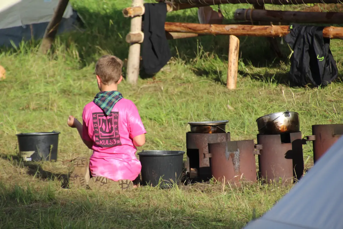 A scout team member preparing food