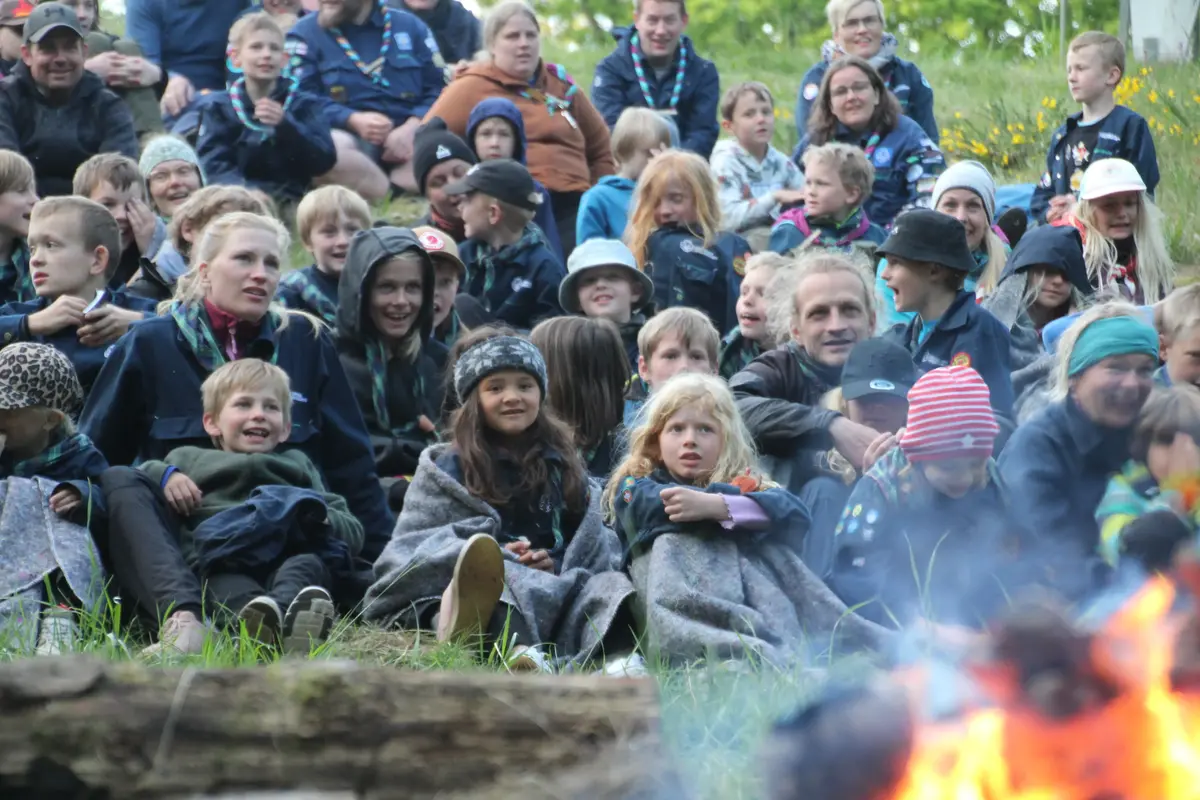 A bunch of kids cozying up under blankets in the wilderness
