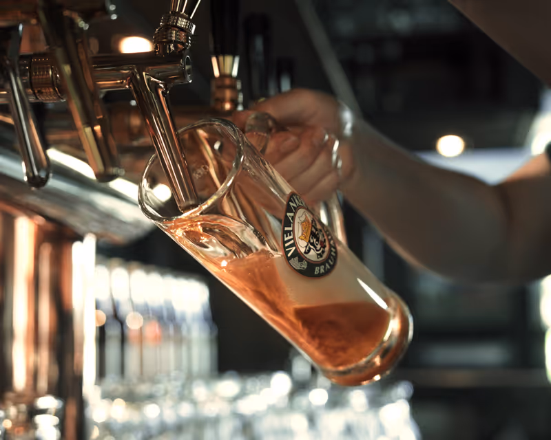 Bierglas mit Vielanker Brauerei-Logo wird unter einem Bierhahn gefüllt.