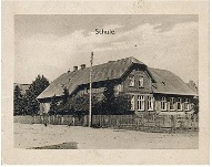 Schwarzweißfoto eines historischen Schulgebäudes mit Beschriftung 'Schule' oben.