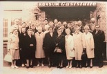 Historisches Schwarz-Weiß-Foto einer Gruppe von Menschen vor einem Gebäude mit der Aufschrift 'KONSUM GENOSSENSCHAFT'.