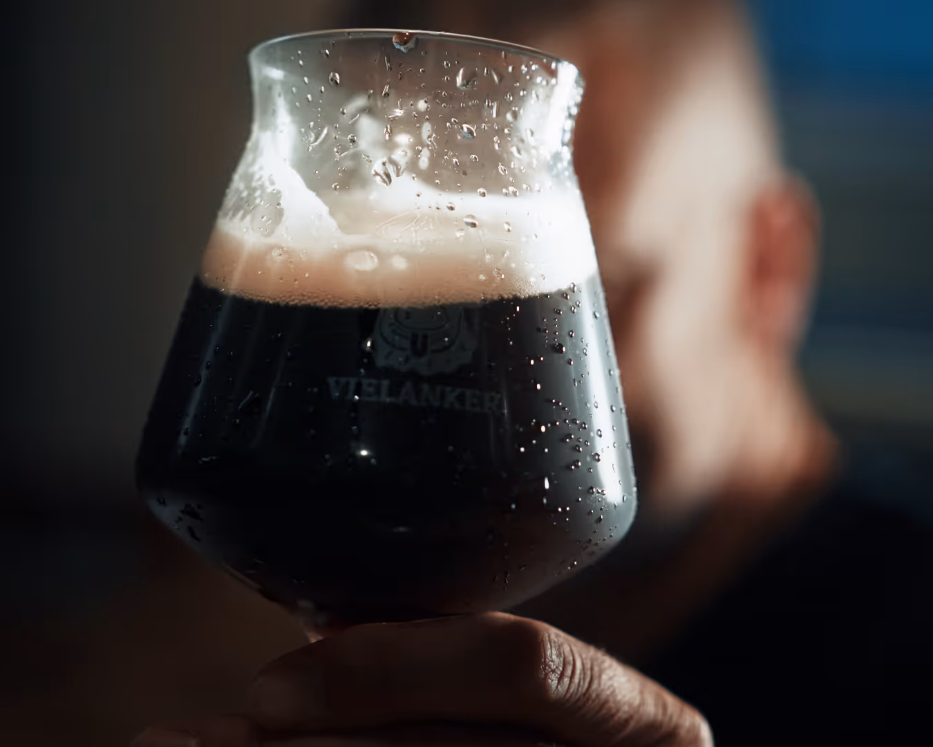 Nahaufnahme eines frisch gezapften dunklen Vielanker Bieres mit feiner Schaumkrone und kühlen Wassertropfen am Glas – purer Genuss.