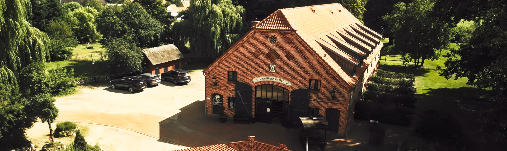 Vogelperspektive auf das Hotel Vielanker Brauhaus: Idyllisch gelegenes Backstein-Ensemble mit ausreichend Parkplätzen für Gäste.