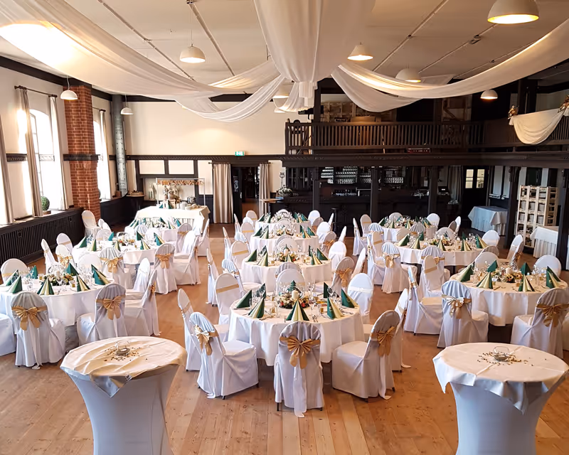 Traumhaftes Hochzeits-Ambiente: Festsaal mit runden Tischen und edlen Stuhlhussen für den perfekten Tag in Vielank.
