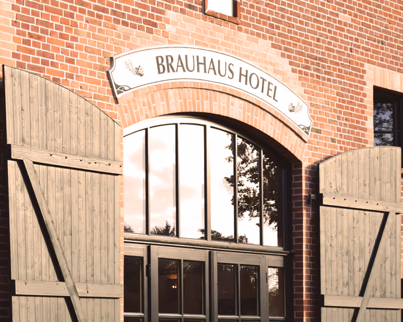 Einladender Eingangsbereich des Hotel Vielanker Brauhaus mit charakteristischem Backsteinmauerwerk und traditionellen grünen Toren.