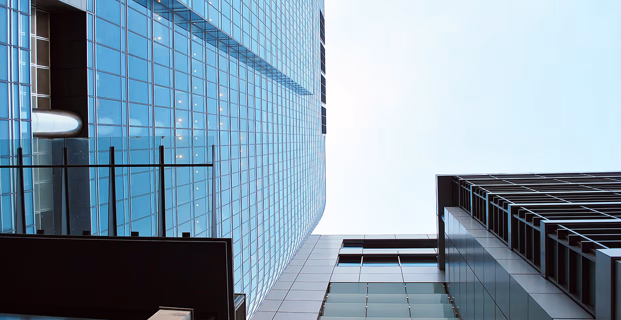 Upward perspective of modern glass and steel skyscrapers against a clear sky.