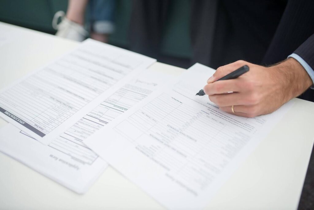 A man writes on a sheet of paper with a pen, focused on his task.