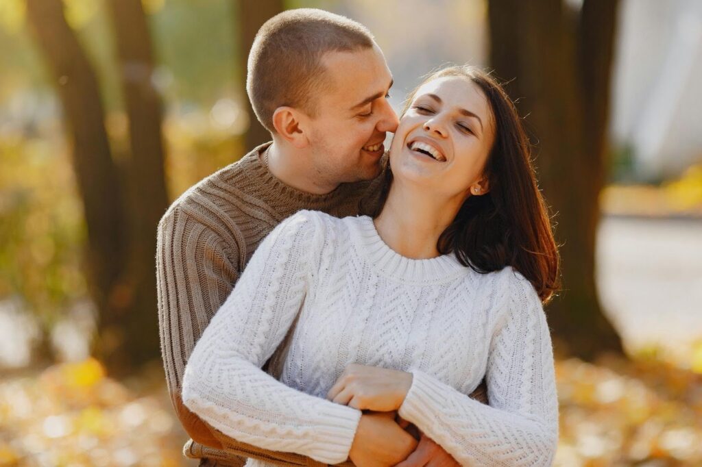 A man and woman embrace warmly in a colorful autumn park