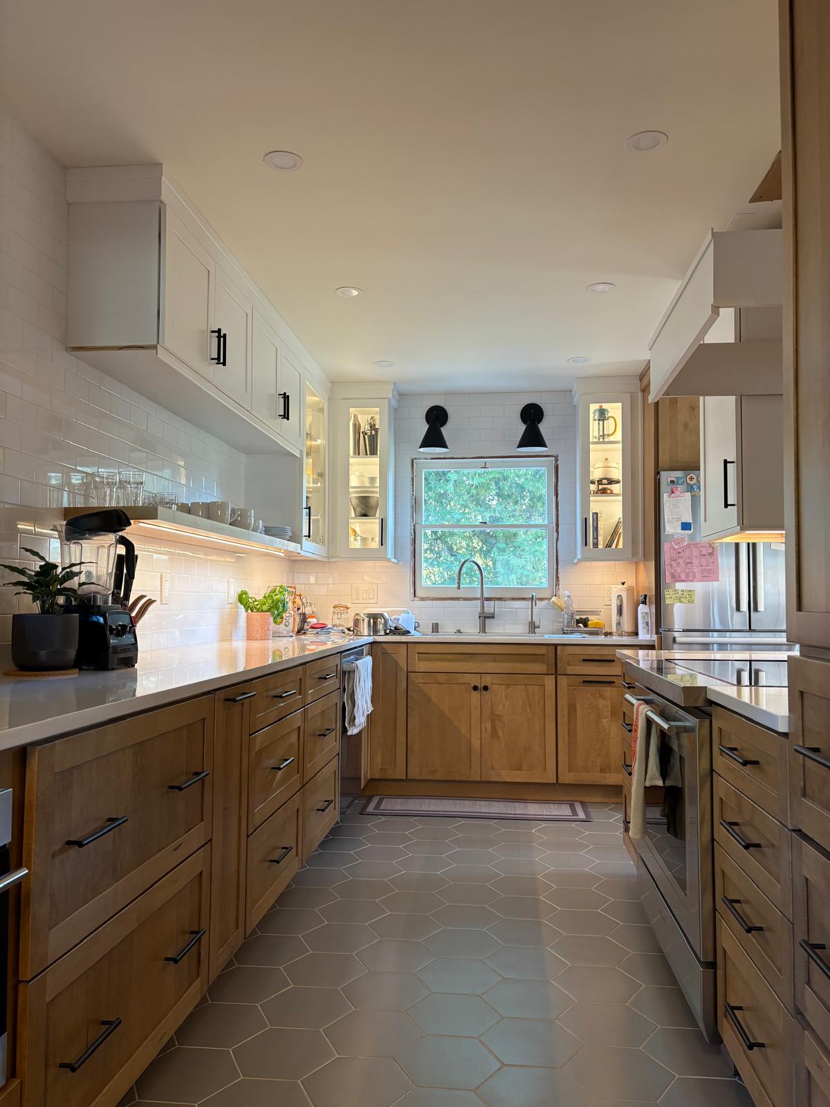 Modern kitchen with natural wood lower cabinets, white upper cabinets, gray hexagon tile flooring, and white subway tile backsplash