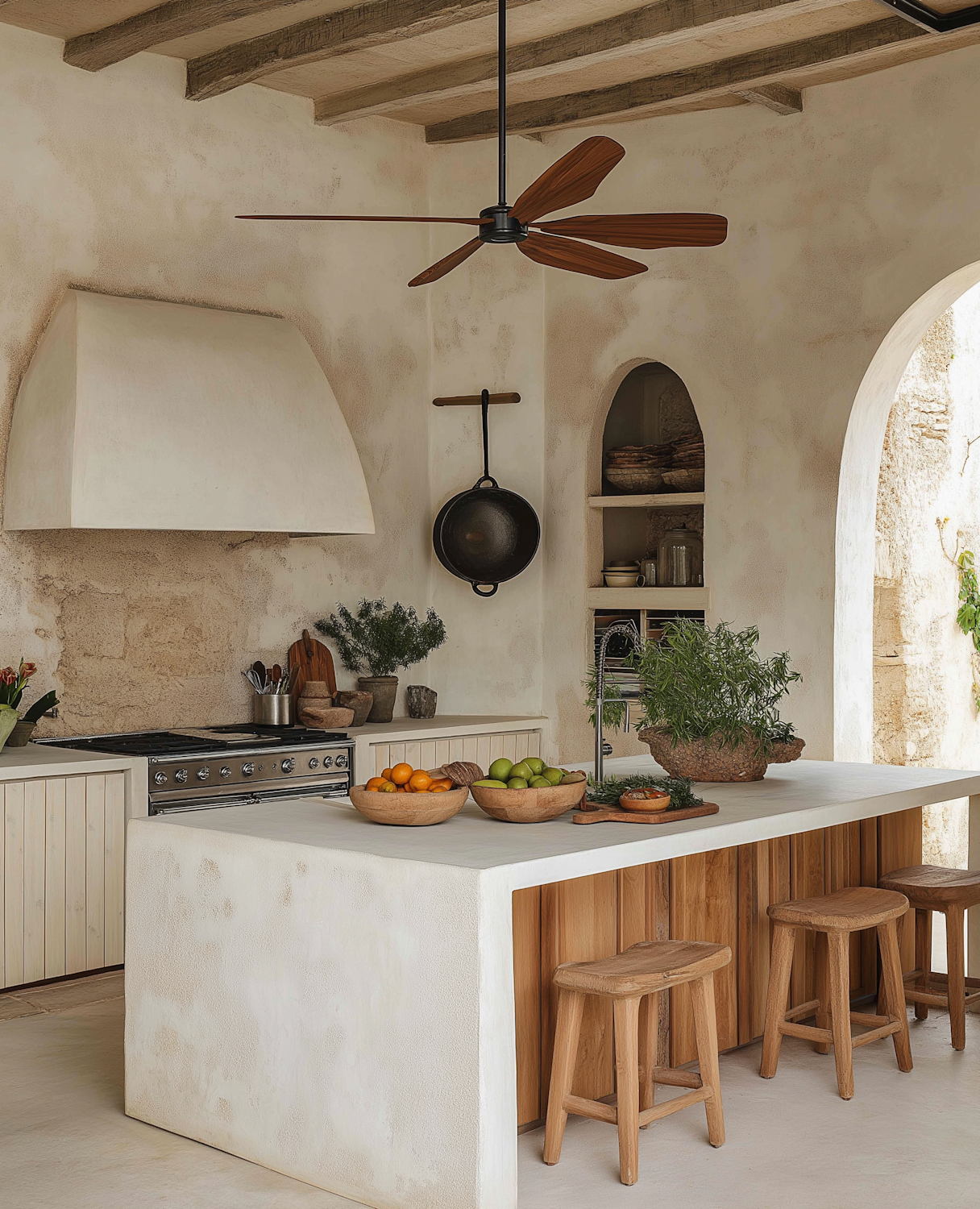 Mediterranean-style kitchen with white plaster island, wood ceiling beams, arched doorway, and wooden bar stools