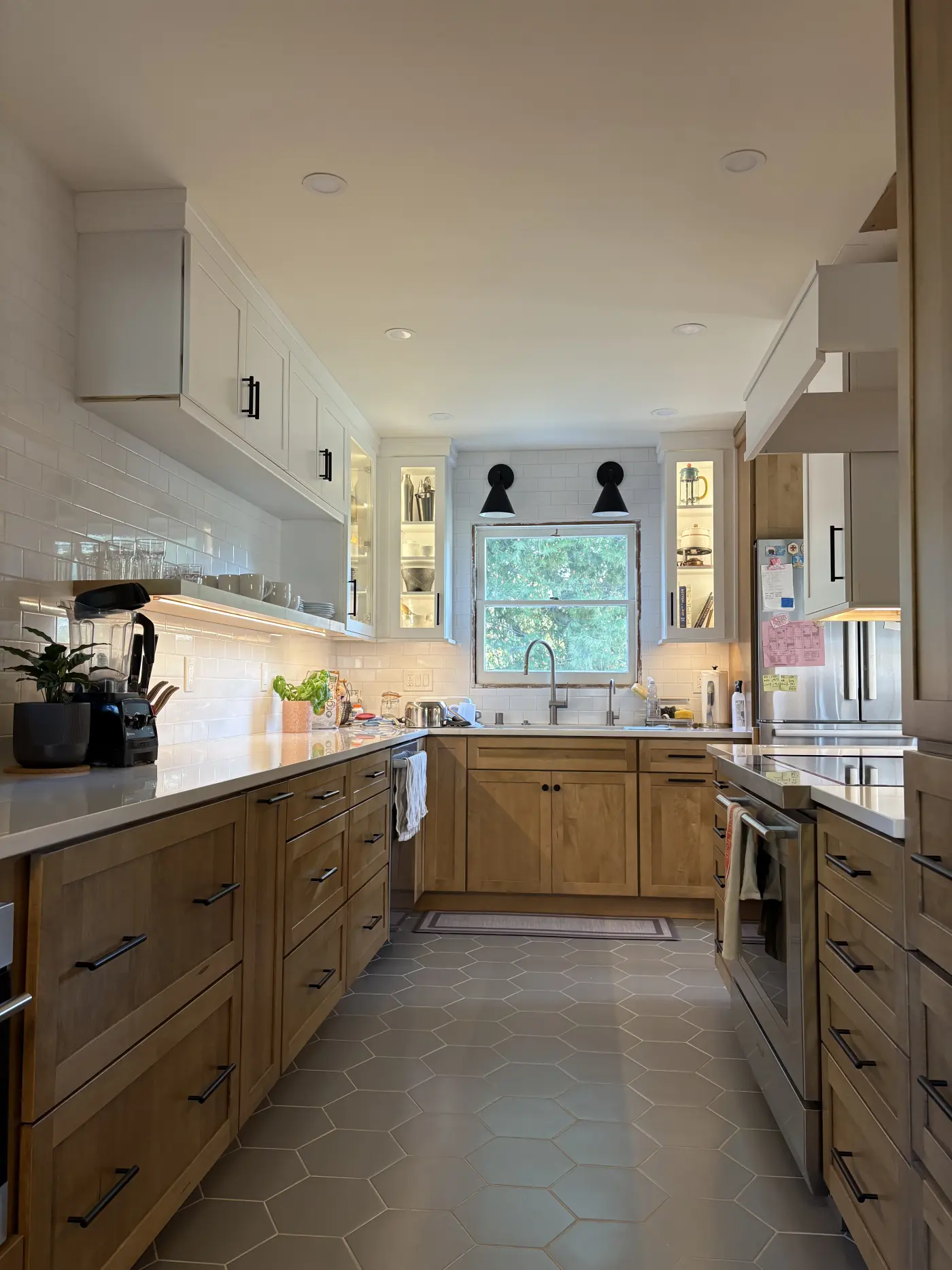 Modern kitchen renovation with light wood lower cabinets, white upper cabinets, gray hexagon tile flooring, and subway tile backsplash