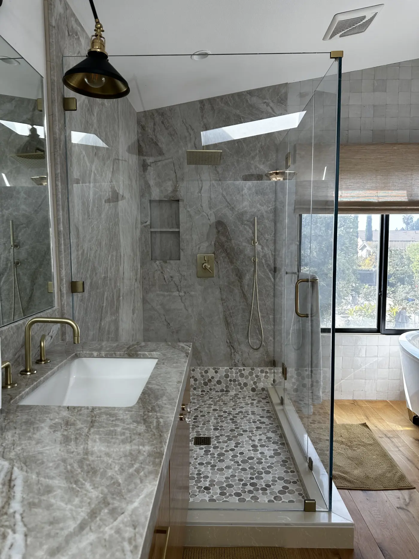 Luxurious marble bathroom with glass shower, brass fixtures, hexagon tile floor, and modern undermount sink