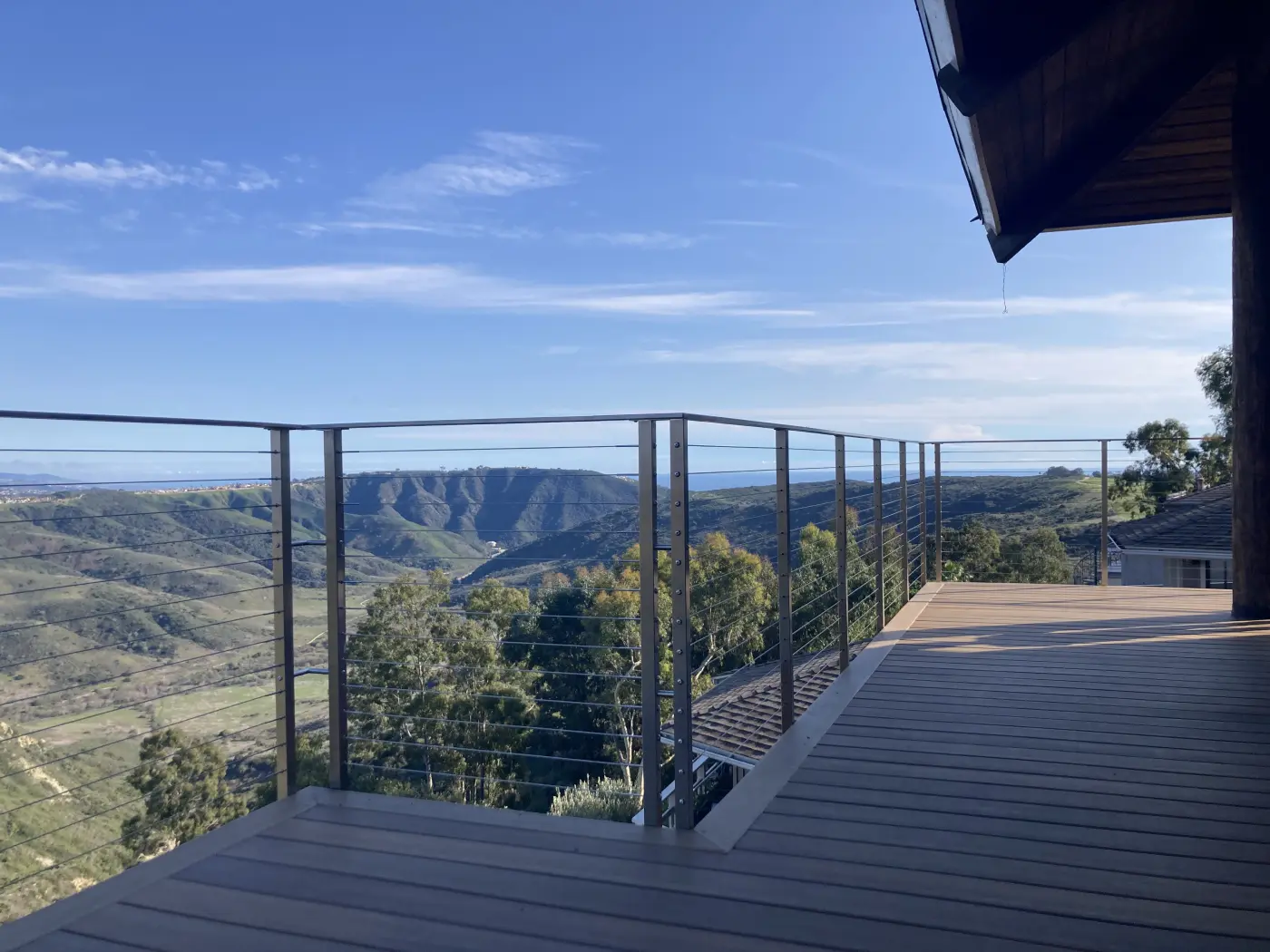 Modern wooden deck with cable railing system overlooking rolling hills and mountains in Orange County, California