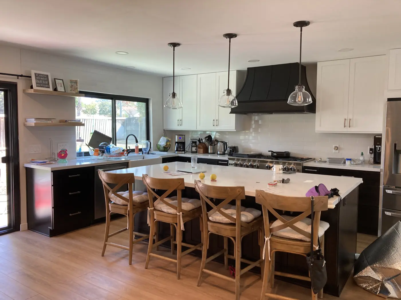 Modern kitchen with white upper cabinets, dark lower cabinets, white quartz countertops, stainless appliances, and wood bar stools