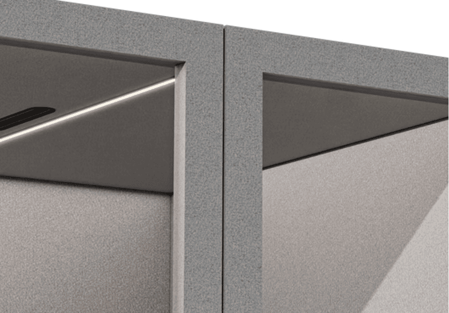 Compact private workspace booth with cushioned seat, small corner desk, and built-in power outlets.