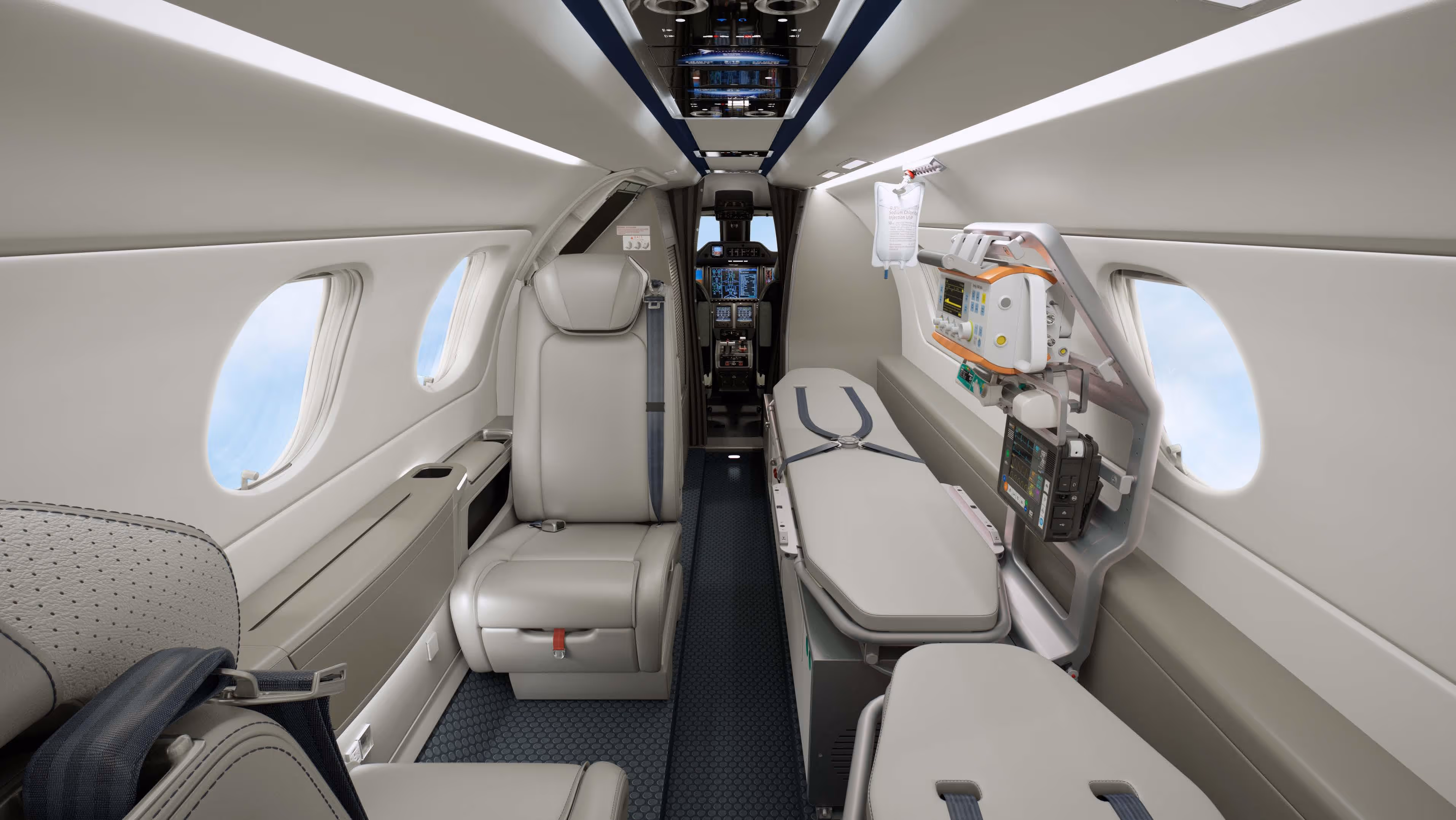 Interior of a medical charter jet featuring a patient stretcher with medical equipment and beige leather seats along the cabin.