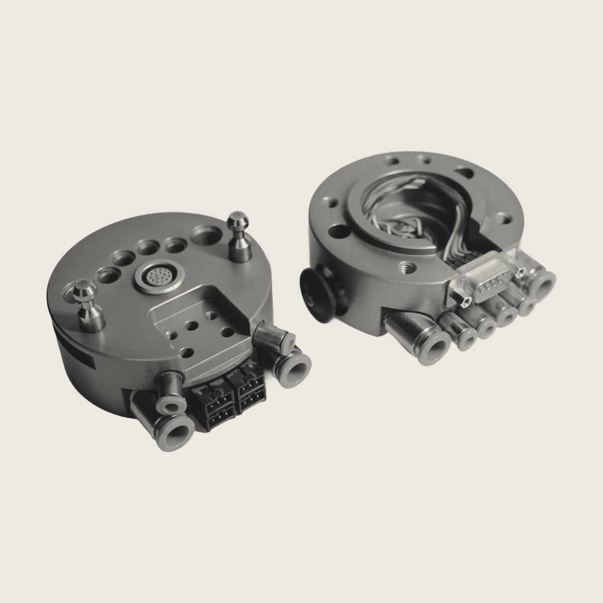 Two metallic circular industrial components with multiple ports and connectors on a light background.