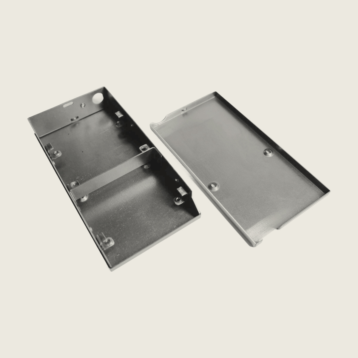 Disassembled black metal rectangular enclosure with base and lid placed side by side.