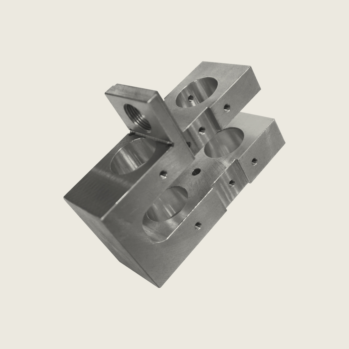 Precision-machined metal component with multiple circular holes and threaded sections on a plain background.