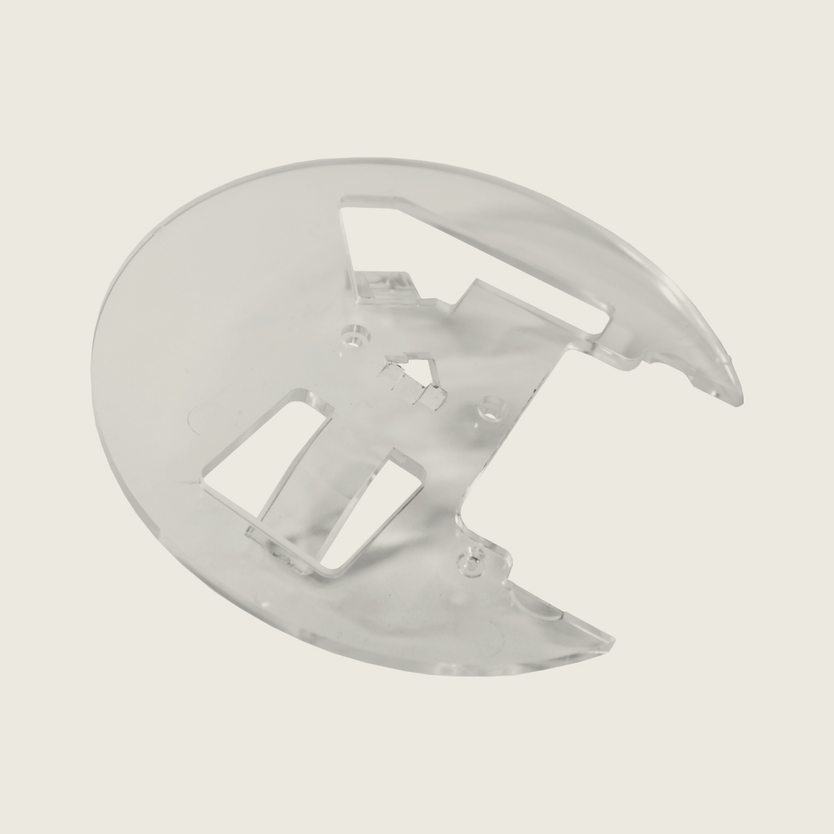 Transparent circular plastic component with cut-out sections on a light background.
