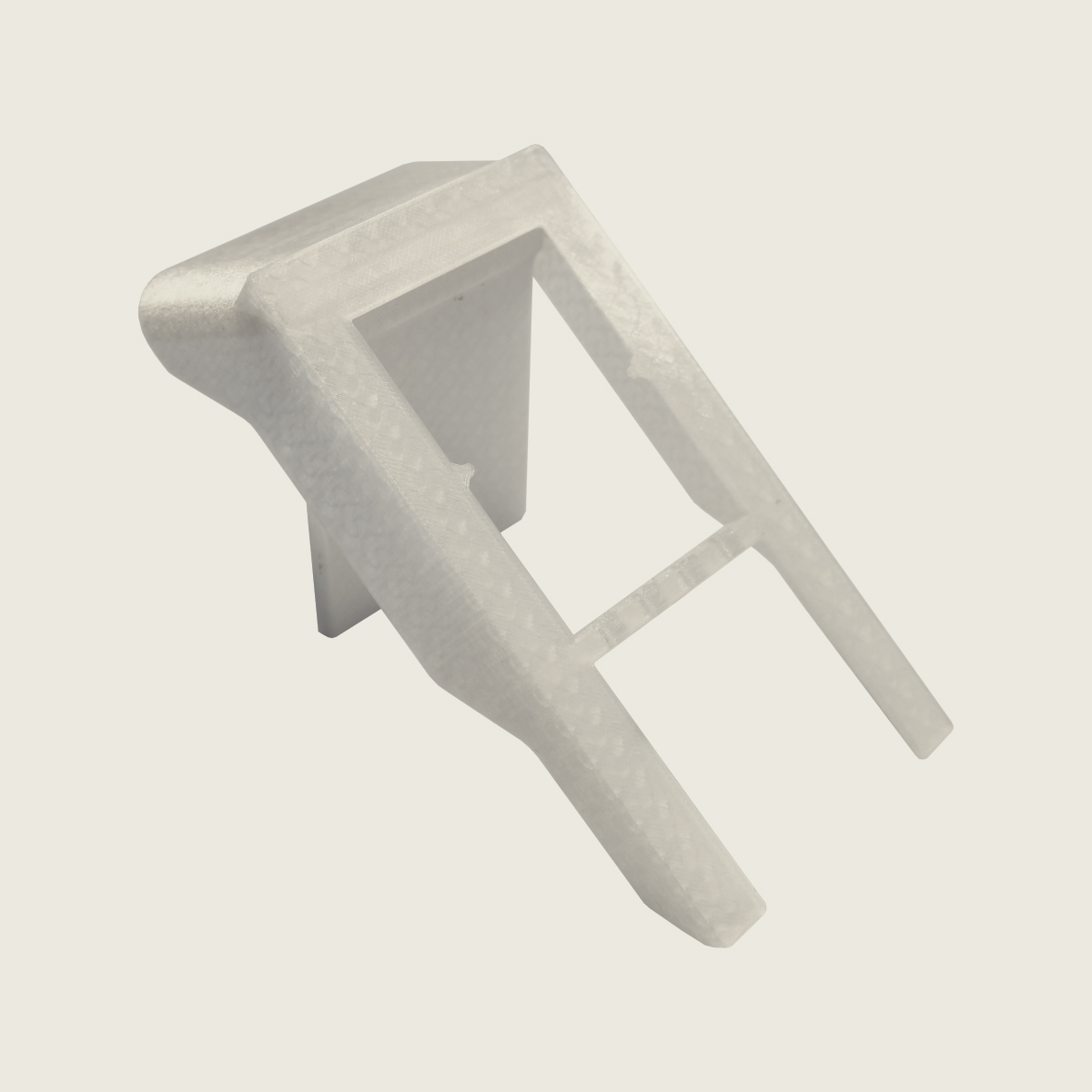 Translucent plastic injection molded component with a rectangular frame and two prongs on a beige background.