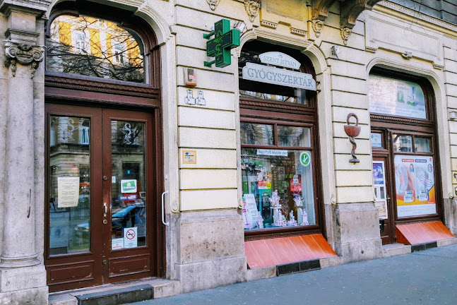A wide river with two passenger boats, surrounded by green trees, a bridge, residential buildings, and hills in the background under a clear sky.