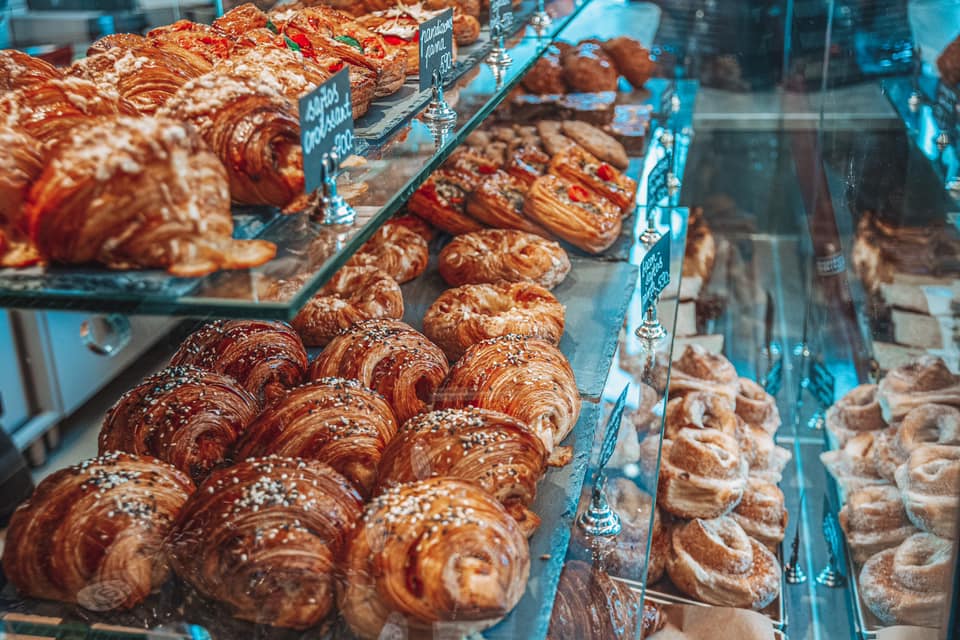 View of Budapest with the Hungarian Parliament building and Chain Bridge across the Danube River, framed by trees with autumn foliage.