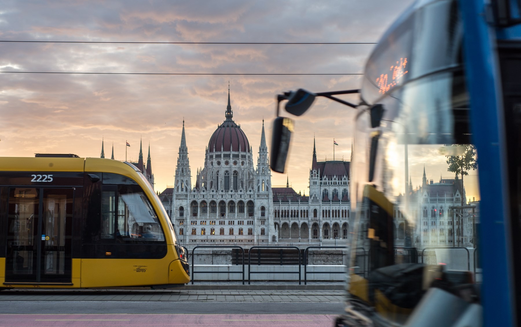 Autumn trees with yellow, orange, and red leaves overlooking the Danube River and the Chain Bridge with the Hungarian Parliament Building in the background.