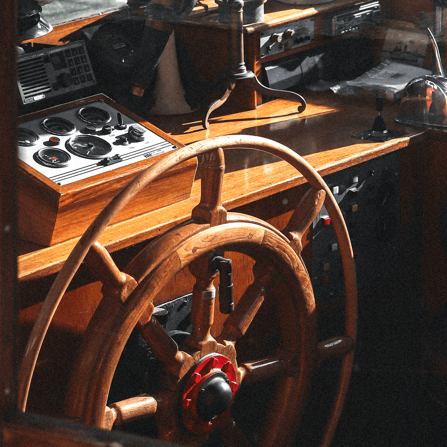 Timón de barco de madera con panel de instrumentos y controles en un puente de mando antiguo.