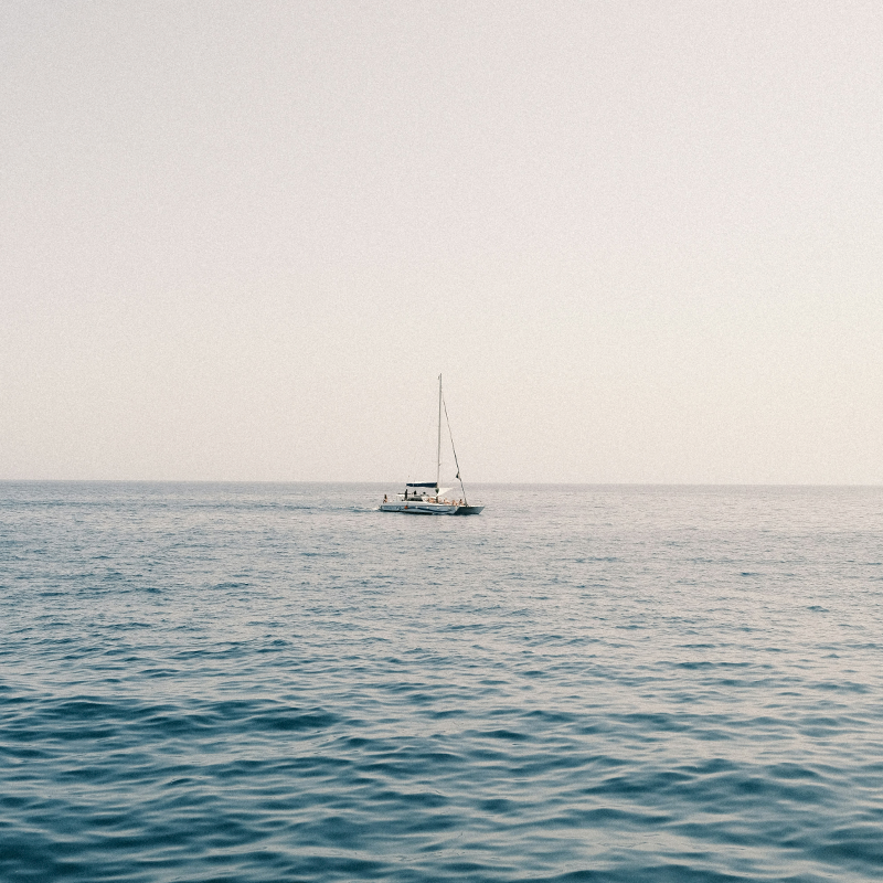Velero navegando sobre un mar tranquilo bajo un cielo claro.