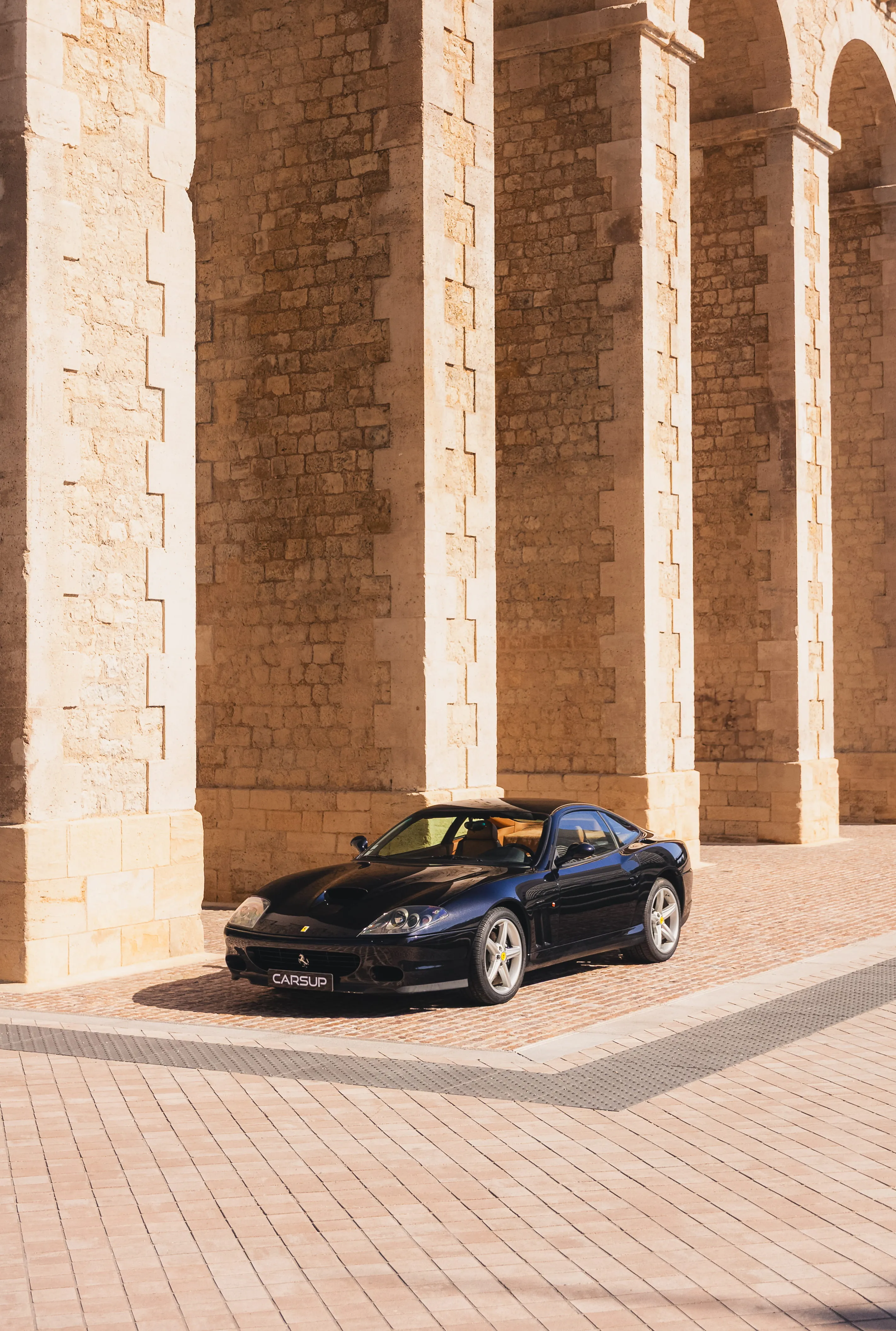 voiture sportive noire devant une architecture en pierre