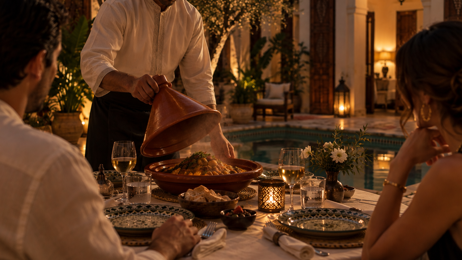 Guests lingering over dinner in a candlelit Moroccan riad courtyard.