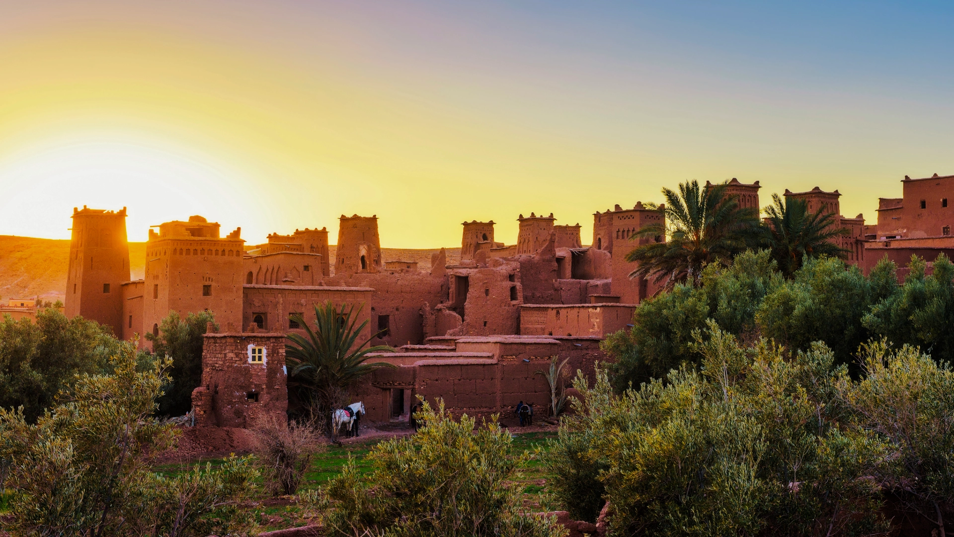 Aït Ben Haddou rising above an oasis landscape in southern Morocco at golden hour