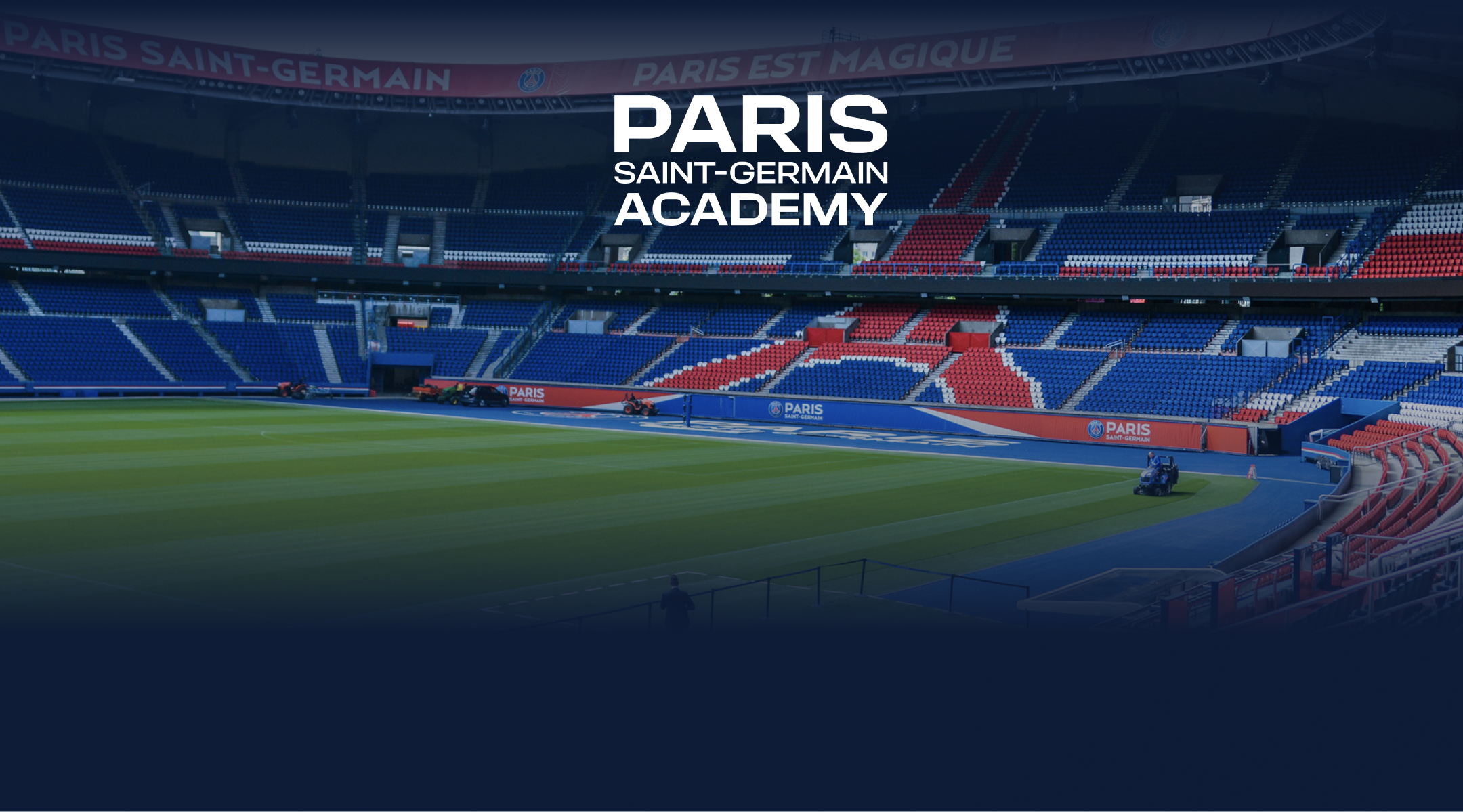 Empty Paris Saint-Germain soccer stadium with green field and seating in blue, red, and white colors.