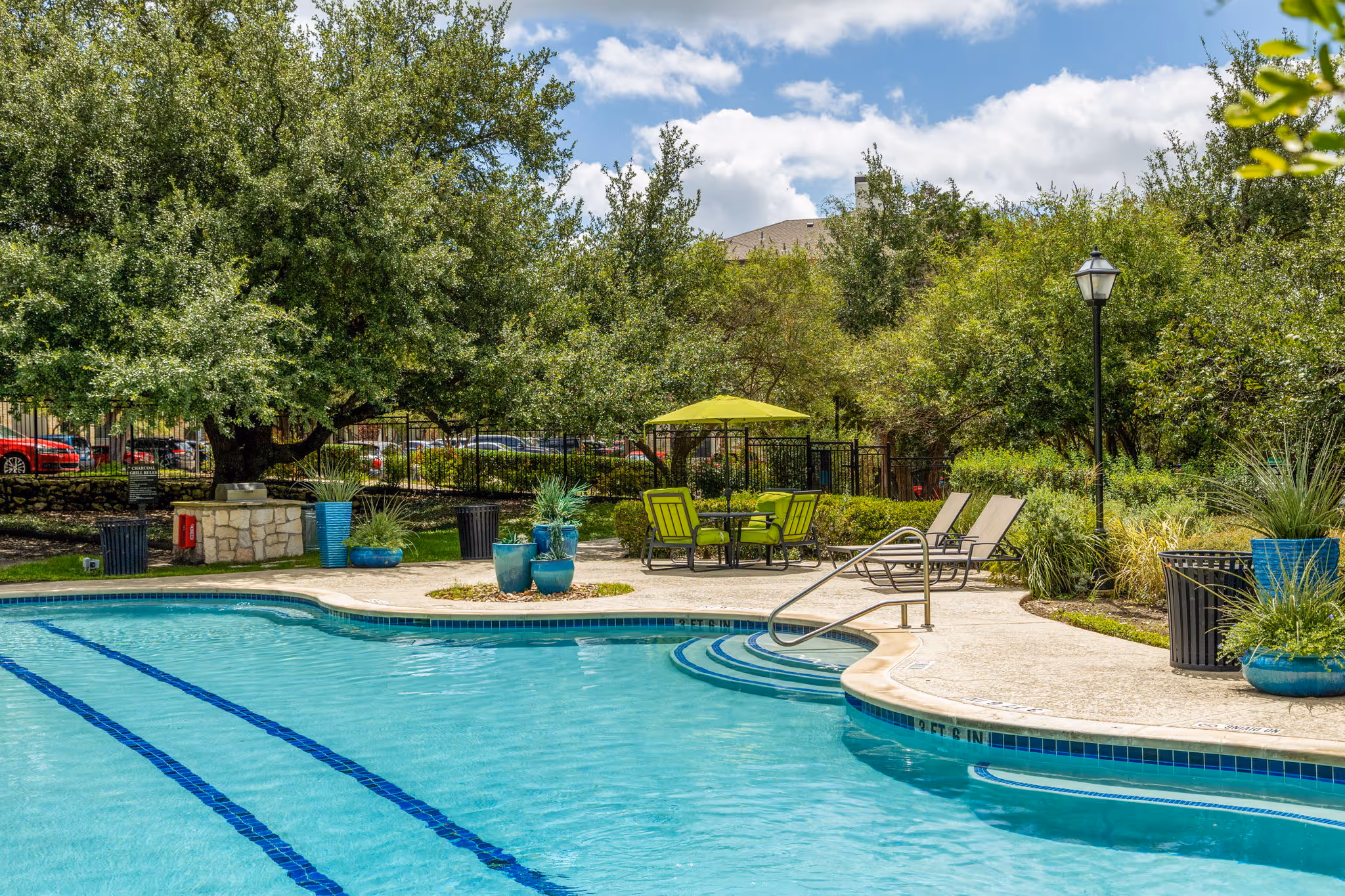 swimming pool with trees and lounge chairs and umbrellas