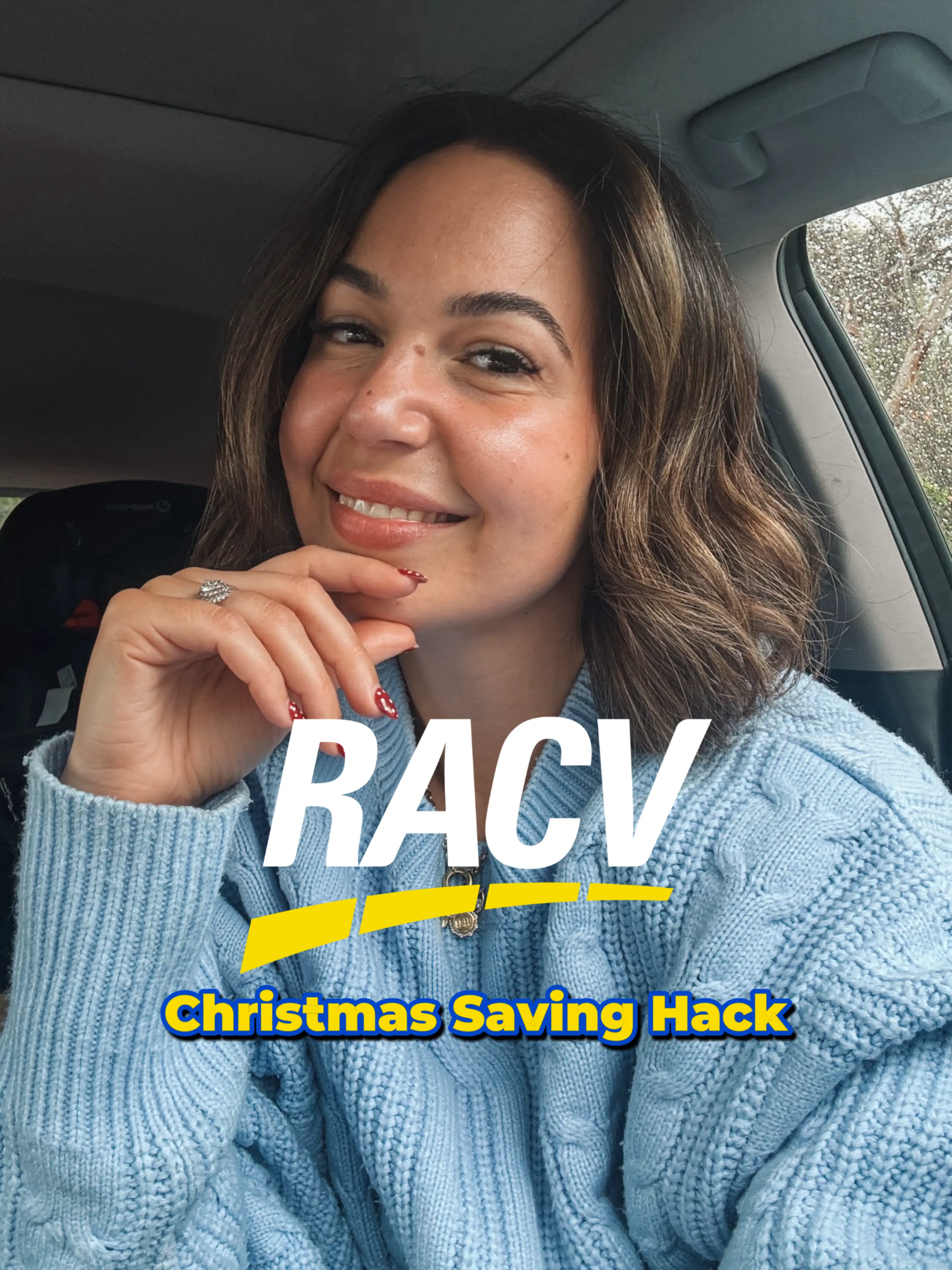 Smiling woman with painted nails wearing a light blue sweater, sitting in a car on a rainy day with text reading 'RACV Christmas Saving Hack'.