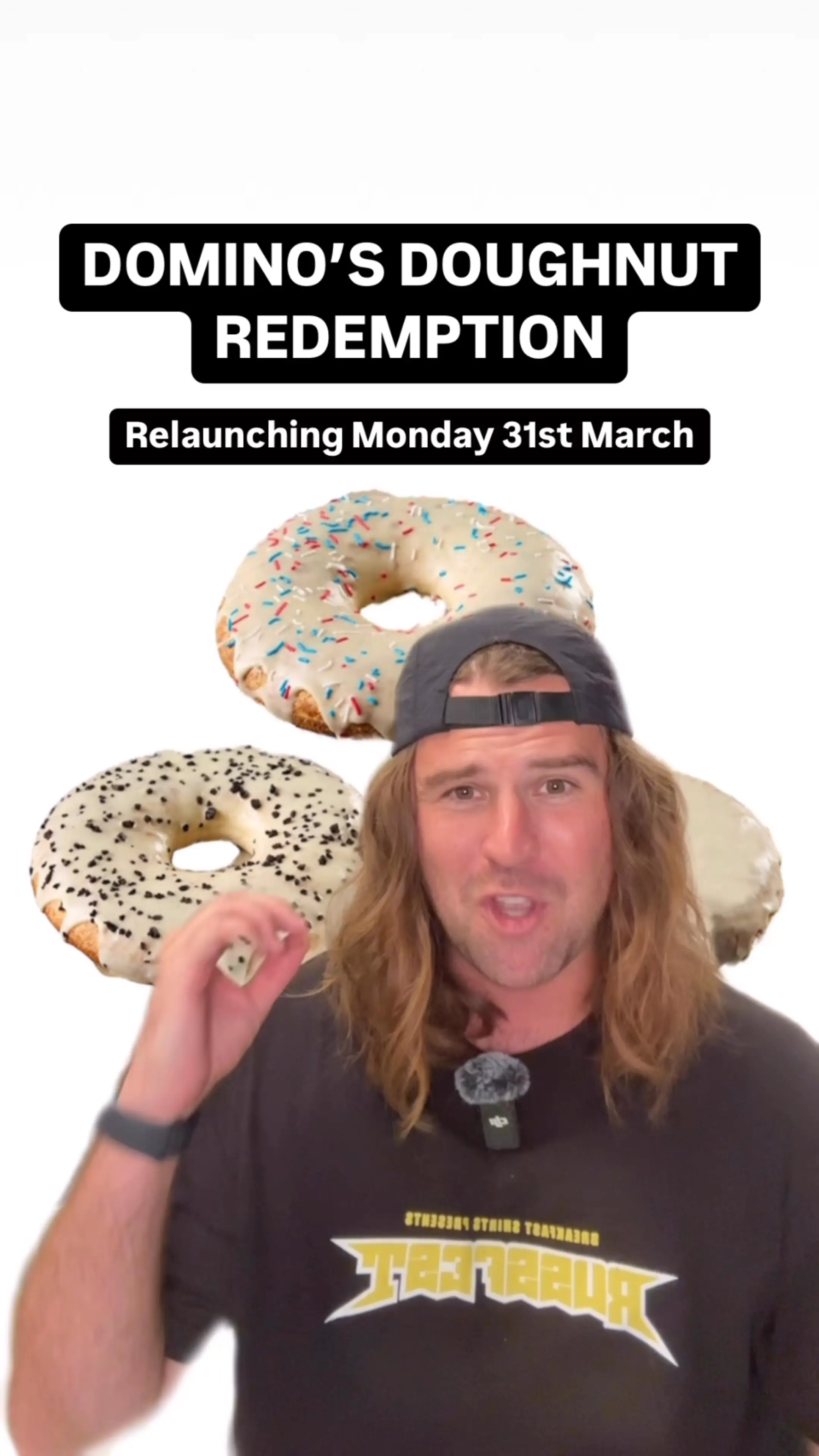 Man with long hair wearing a backward cap and a black shirt stands in front of three large sprinkled doughnuts with text announcing Domino’s Doughnut Redemption relaunch on Monday 31st March.