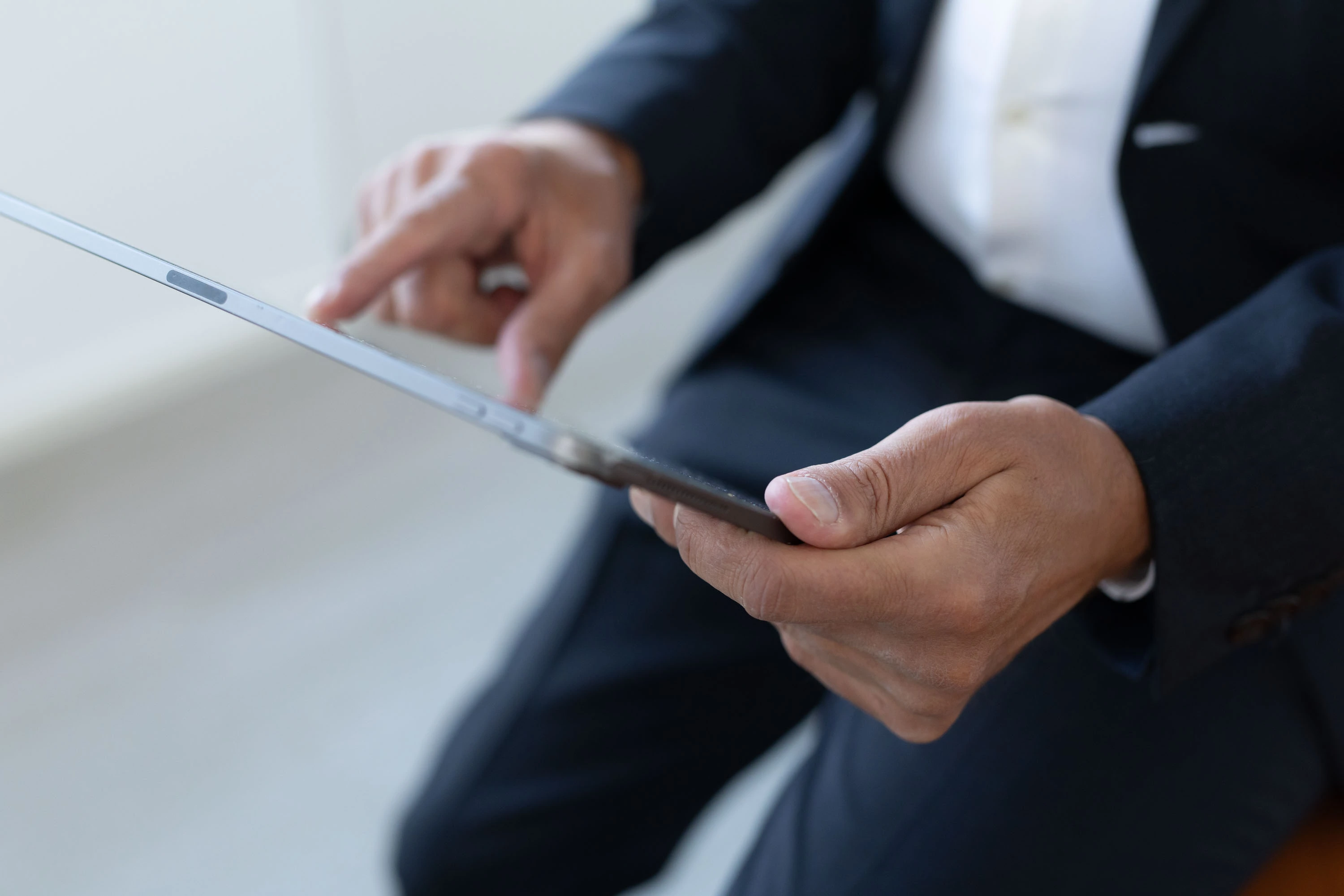 Markus Lesser in einem dunklen Anzug bedient ein Tablet mit den Händen.