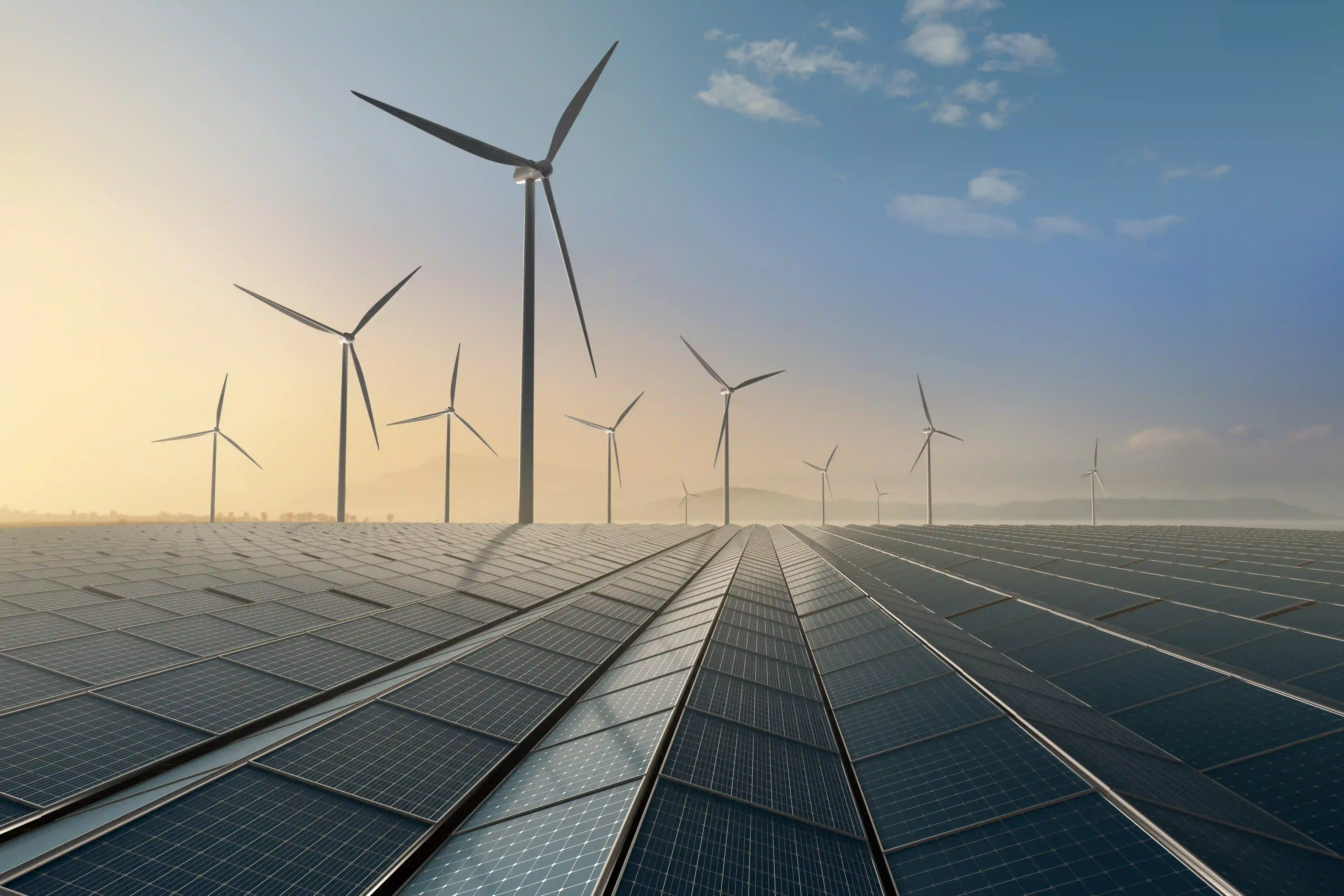 Großes Solarfeld mit mehreren Windturbinen im Hintergrund bei Sonnenaufgang oder -untergang.