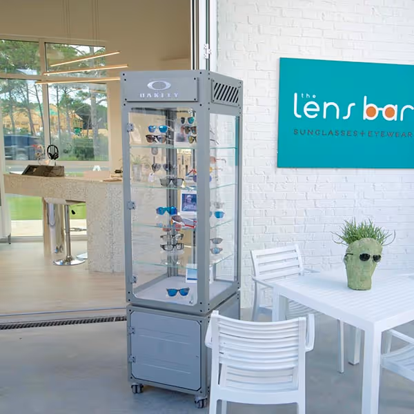 Elegant wine cellar with wooden racks filled with wine bottles, a wooden island table holding a wine bottle and glass decanters, illuminated by a modern golden chandelier.