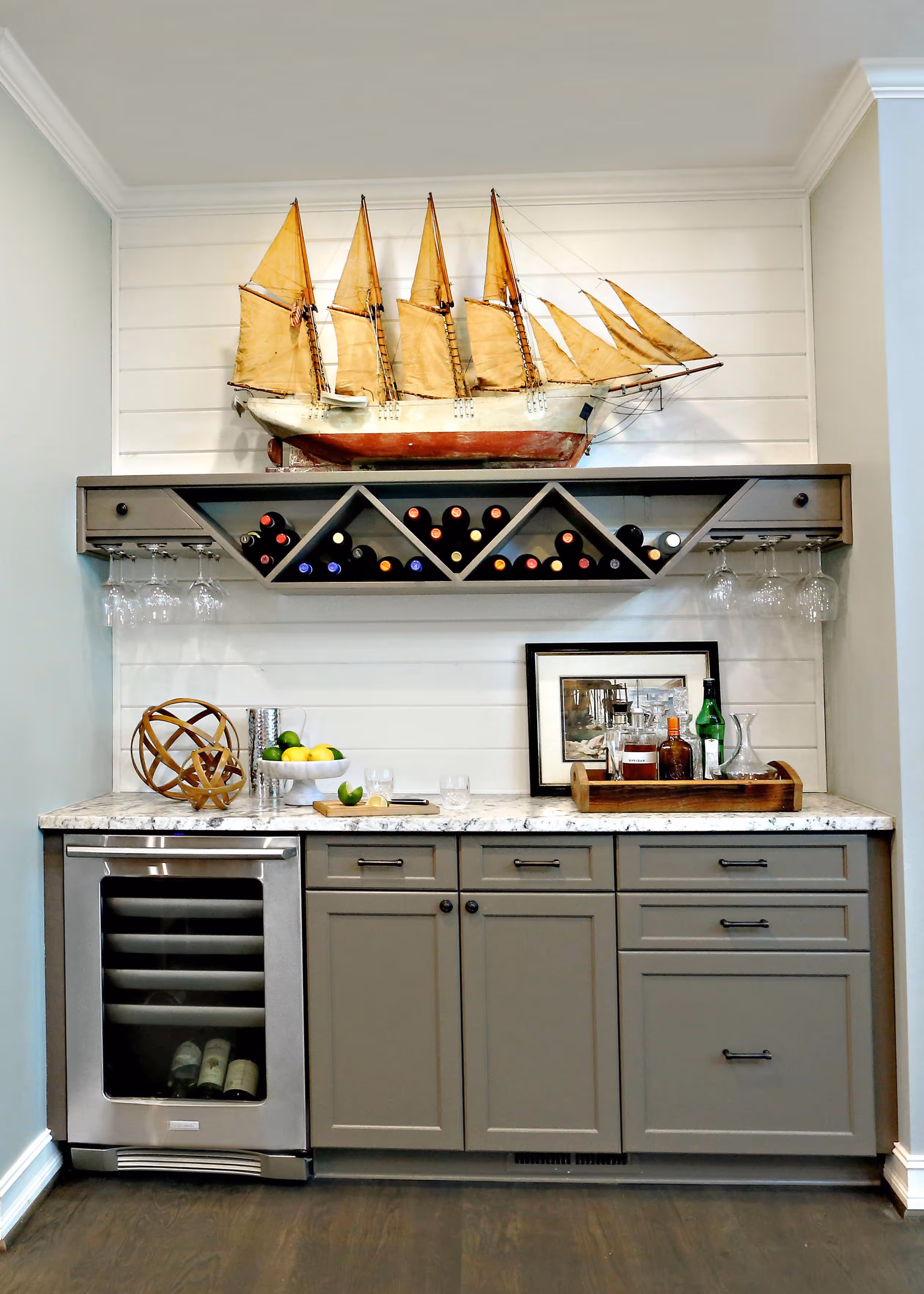 Sunny porch with two metal and mesh chairs, stone half-wall, metal railing, and green trees in the background.