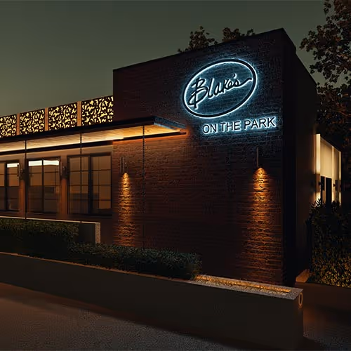 Modern kitchen and dining area with a wooden table, red chairs, marble countertops, white cabinets, wine rack, and decorative model ship.