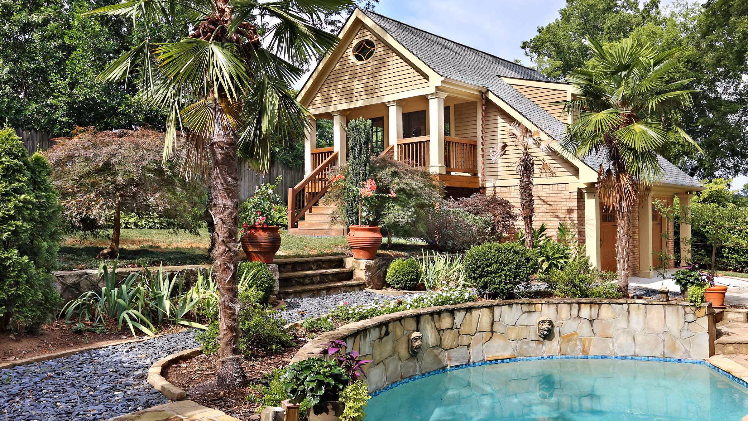 Modern kitchen with a wooden dining table surrounded by red leather chairs, white cabinetry, and a countertop with a bowl of colorful bell peppers.