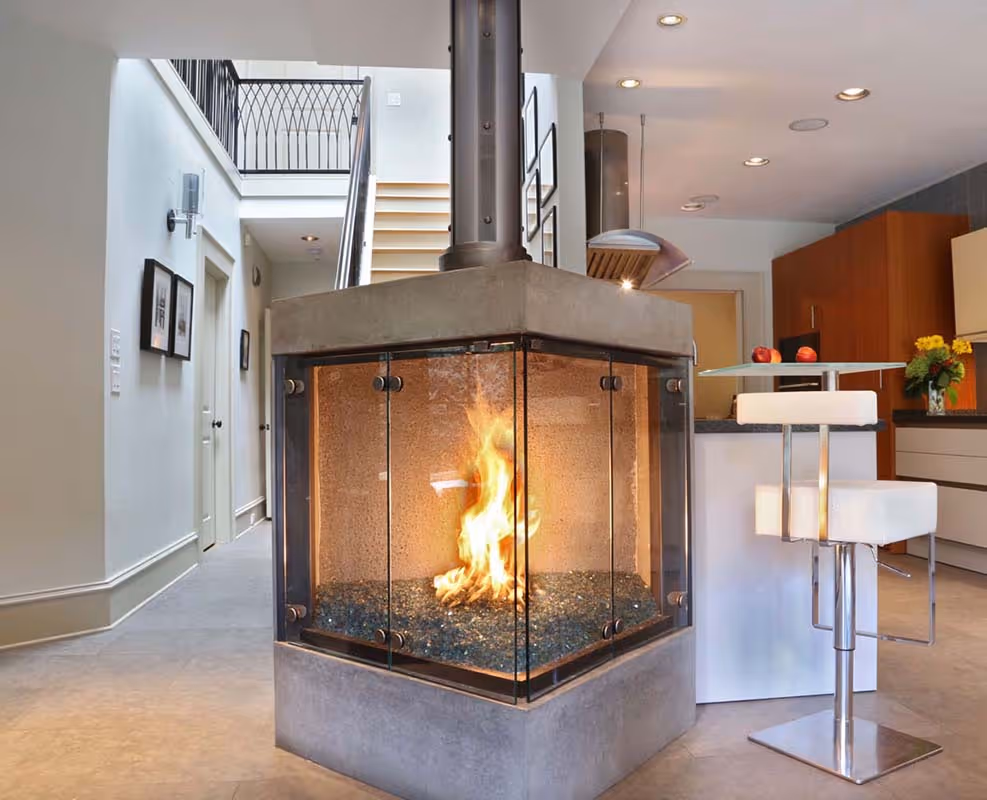 Two modern two-story apartment buildings with beige and brown exteriors surrounded by green lawns and autumn trees under a partly cloudy sky.