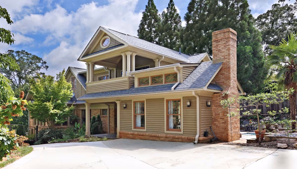 Elegant wine cellar with wooden racks filled with bottles, a central wooden table holding a wine bottle and glass decanters, and a gold-colored chandelier overhead.