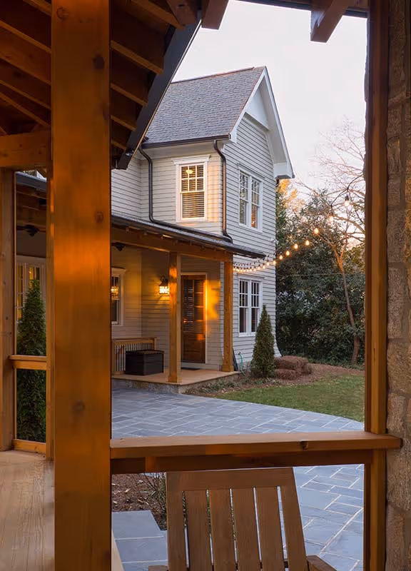 Two-story residential buildings with brick and beige exterior, surrounded by green lawns and autumn trees under a partly cloudy sky.